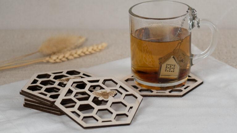 Set van zes houten bijenonderzetters met honingraatmotief en theeglas op linnen doek