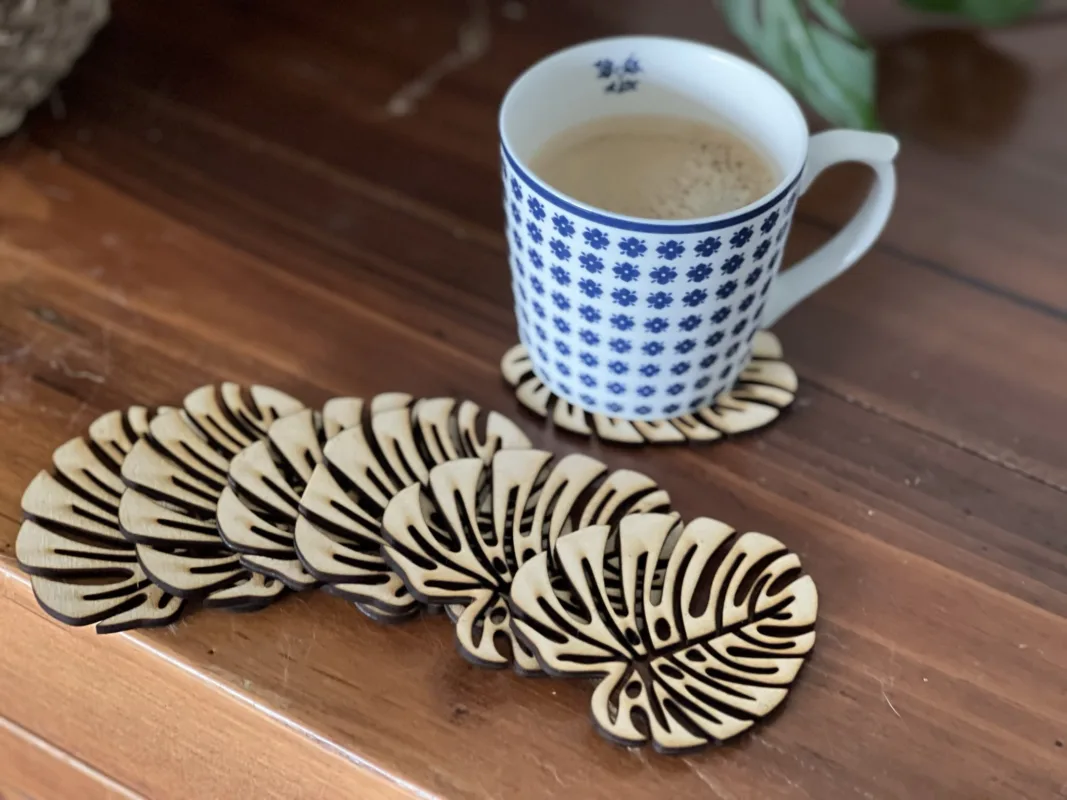 Houten Monstera onderzetters op een tafel met groene planten.