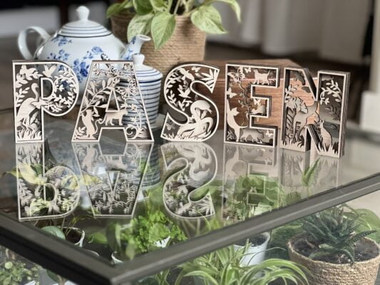 Een afbeelding van botanische houten letters, met kleurrijke planten en dierenmotieven, perfect om je huis op te fleuren.