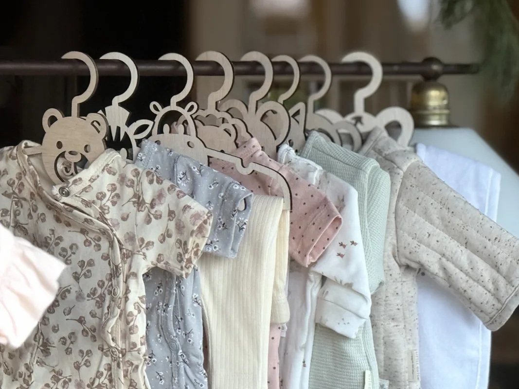 Groepsfoto van 15 handgemaakte houten babykledinghangers in dierenvormen met schattige babykleding – perfect kraamcadeau en babykamer decoratie