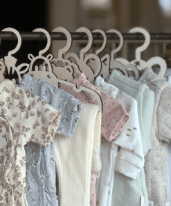 Groepsfoto van 15 handgemaakte houten babykledinghangers in dierenvormen met schattige babykleding – perfect kraamcadeau en babykamer decoratie