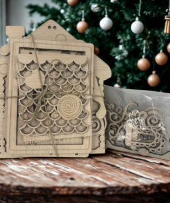 Houten decoratieve snijmal in de vorm van een huis met een verpakking ernaast, geplaatst op een houten tafel.