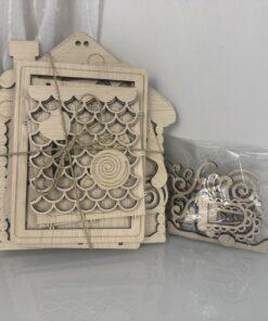 Houten decoratieve huisvorm met gedetailleerde snijwerk en losse onderdelen in een plastic zak.