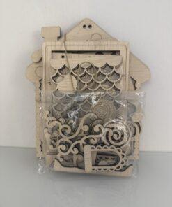 Houten decoratieve elementen verpakt in een doorzichtige zak met een huisvormige achtergrond.