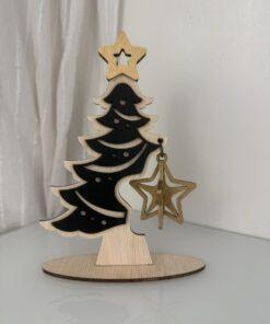 Houten kerstboom met een zwarte vorm en een gouden ster ornament aan een tak.