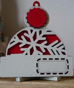 Houten kerstdecoratie met een sneeuwvlok en een rood accent, geplaatst op een houten oppervlak.