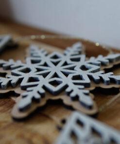 Houten sneeuwvlok ornament met een gedetailleerd ontwerp en een gouden draad voor ophangen.