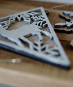 Houten kerstdecoraties in de vorm van een hert en een sneeuwvlok, geplaatst op een houten oppervlak.