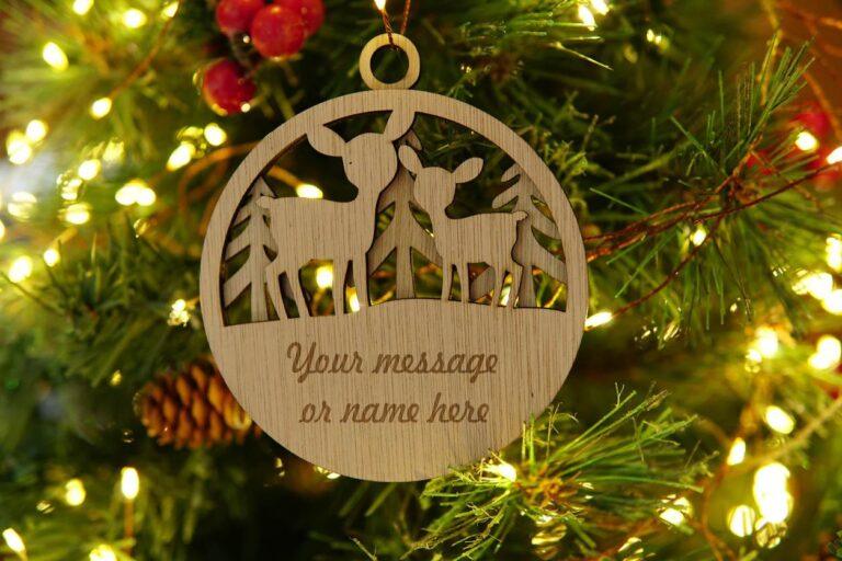 Houten kerstornament met twee herten en de tekst 'Your message or name here' in een groene dennenboom.