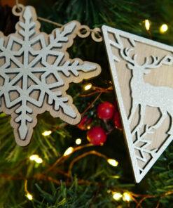 Houten kerstdecoraties in de vorm van een sneeuwvlok en een hert, hangend aan een tak met verlichting.