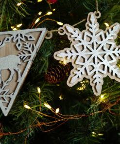 Houten kerstornamenten in de vorm van een rendier en een sneeuwvlok, hangend aan een kerstboom.