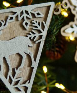 Houten ornament in de vorm van een driehoek met een hert en sneeuwvlokken, versierd met glitter.