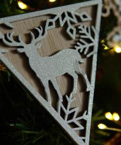 Houten kerstornament in de vorm van een driehoek met een hert en sneeuwvlokken.