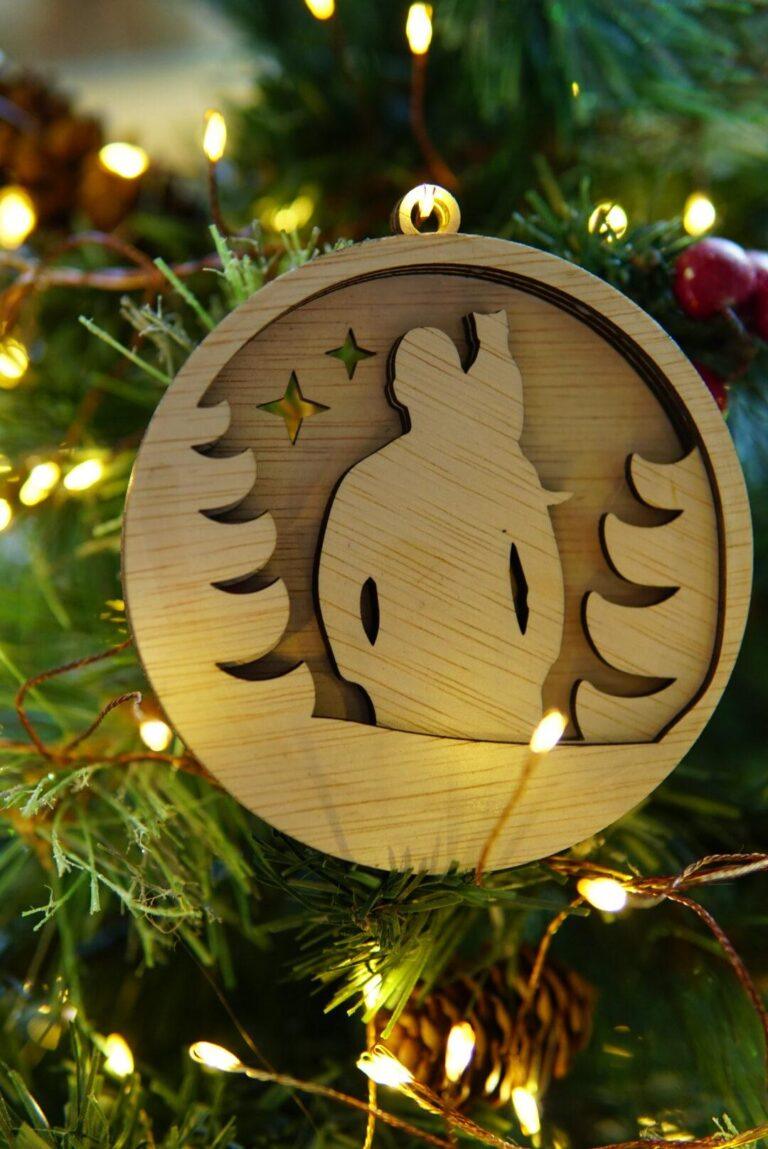 Houten kerstornament met man en kat op schouder tussen kerstbomen