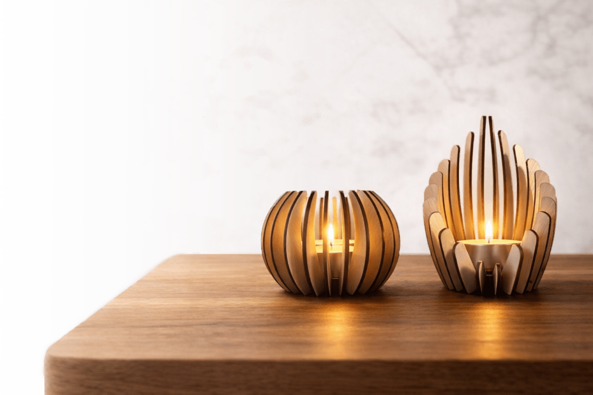 Twee houten kaarsenhouders met een moderne uitstraling, geplaatst op een houten oppervlak.